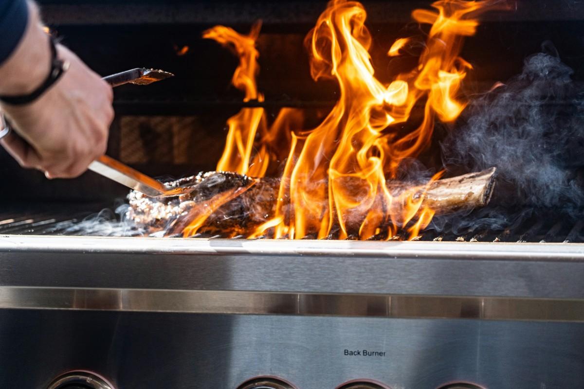 A steak engulfed in flames on an open grill