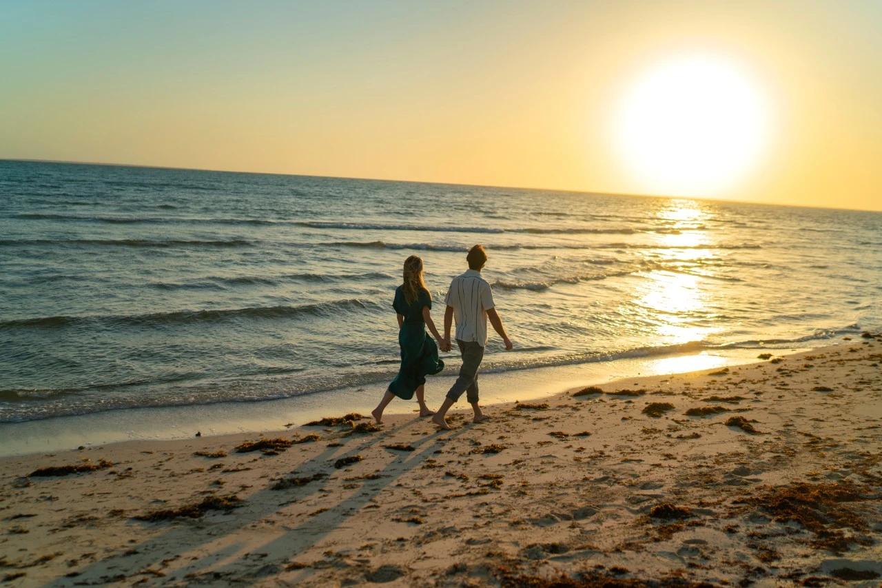A couple strolling along a beach near Jeddah at sunset